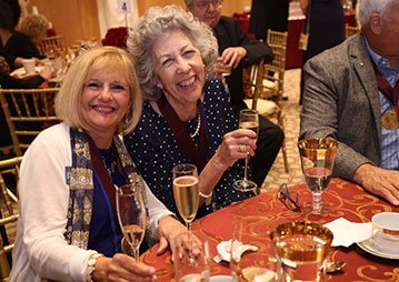 Two women smiling at a planned giving celebration dinner. Links to Gifts by Will Two women smiling at a planned giving celebration dinner. Links to Gifts by Will